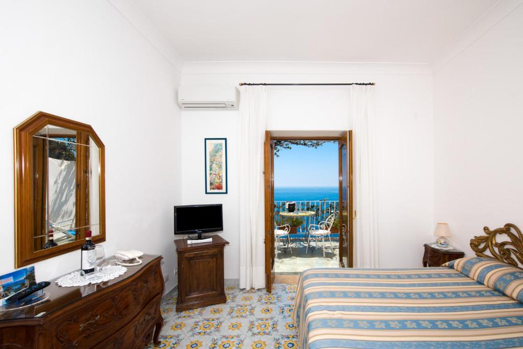1 dormitorio con cama, espejo y TV en La Rosa Dei Venti en Positano