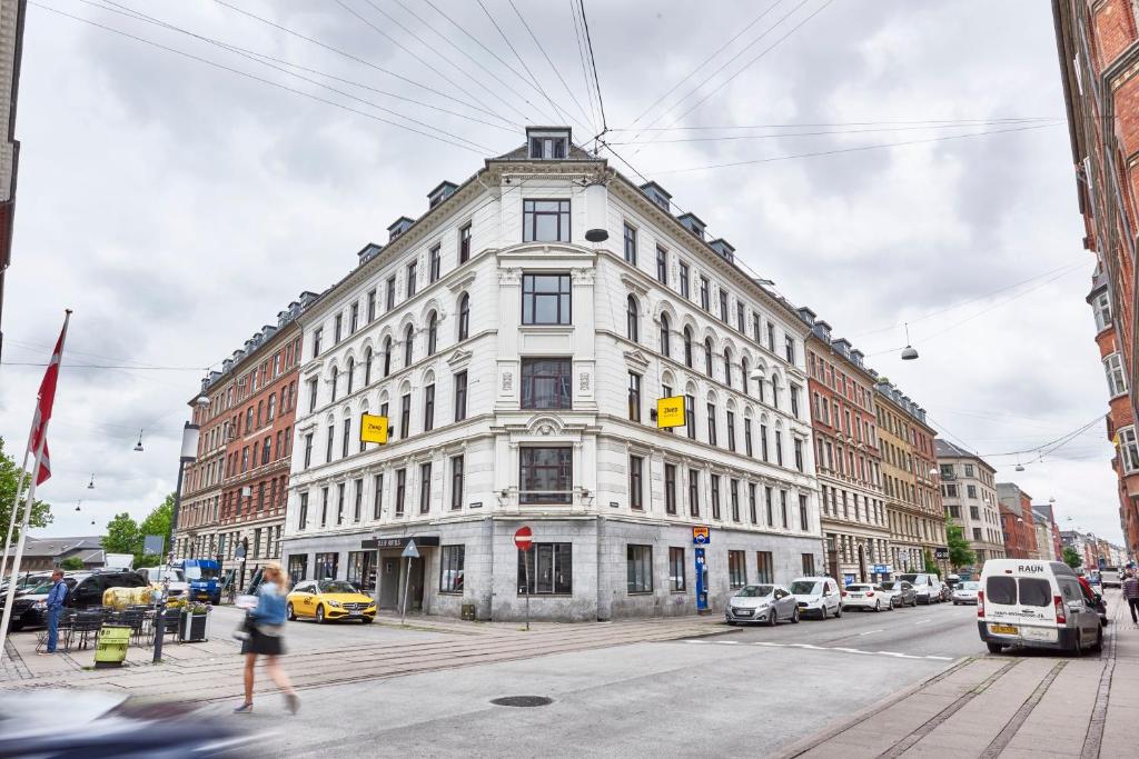un gran edificio blanco en una calle de la ciudad con coches en Zleep Hotel Copenhagen City, en Copenhague