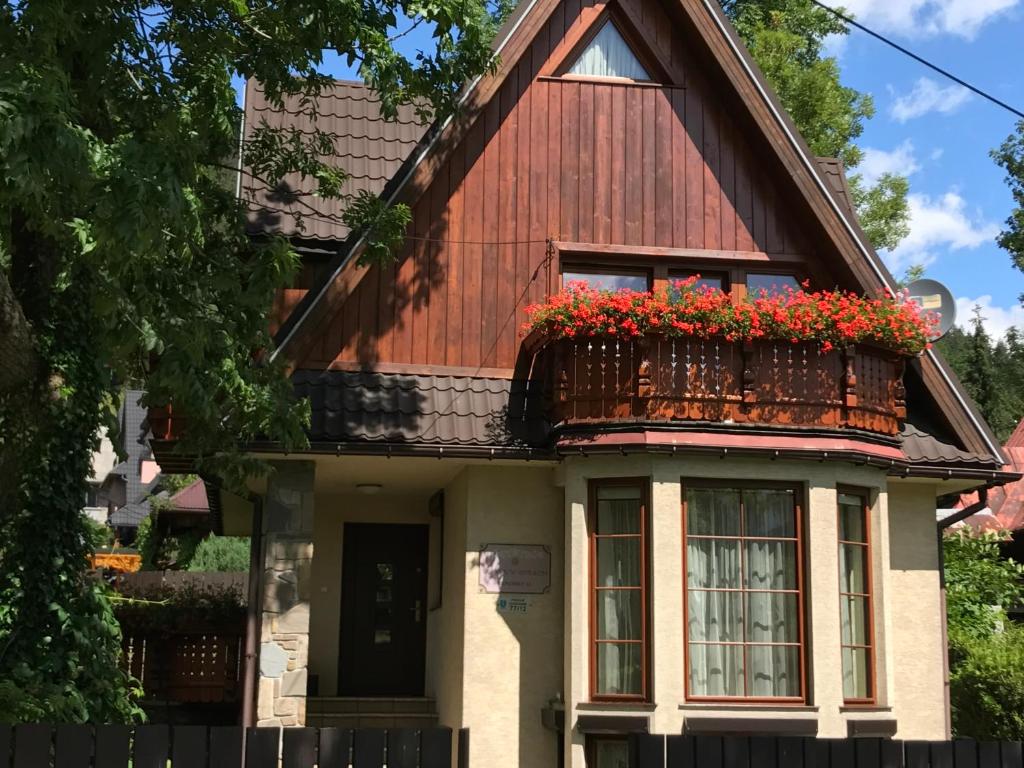 Domek w Górach - Przy Potoku في زاكوباني: منزل مع شرفة عليها زهور حمراء