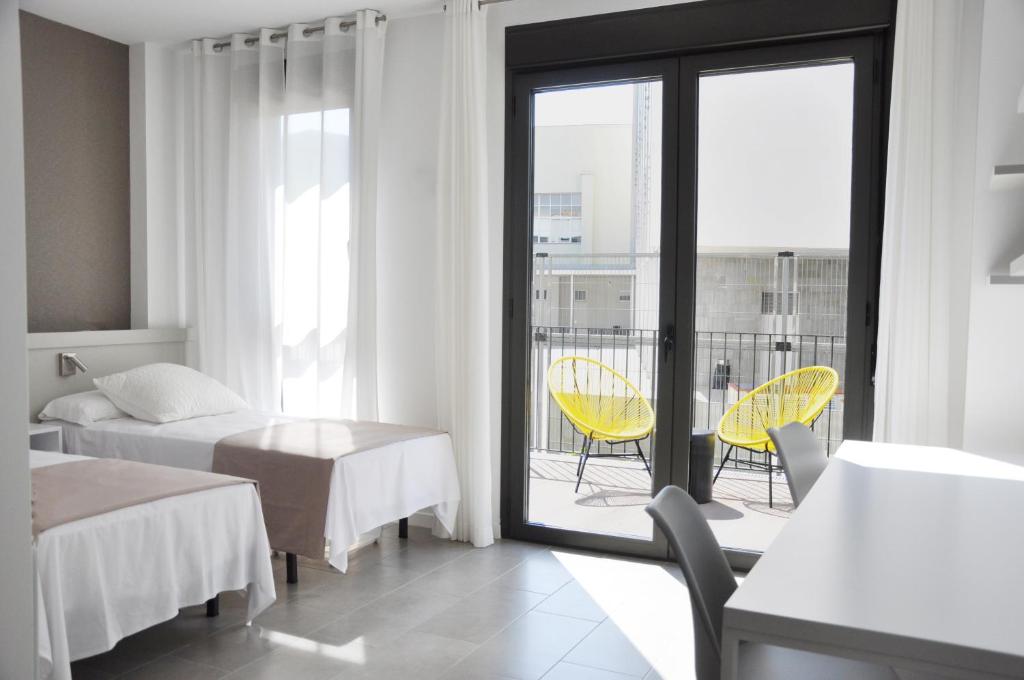 a hotel room with two beds and a balcony at Residencia Universitaria Tarragona Mediterrani in Tarragona