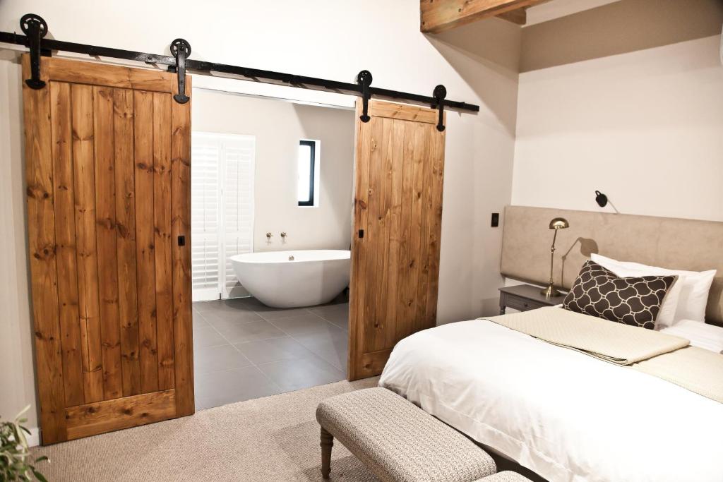 a bedroom with a wooden sliding door and a bath tub at d'Olyfboom Guest House B & B in Paarl