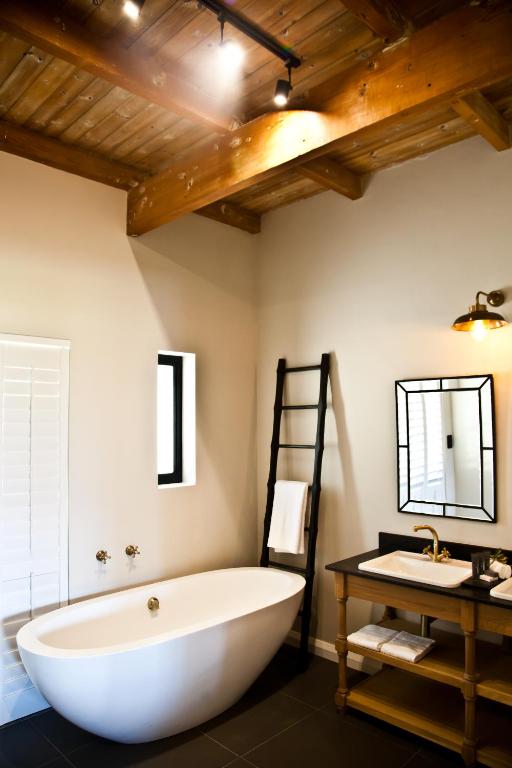 a large white bath tub in a bathroom with a sink at d'Olyfboom Guest House B & B in Paarl
