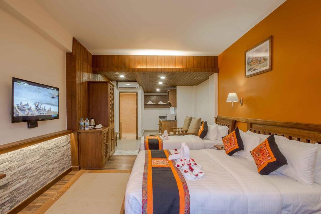 Habitación de hotel con 2 camas y TV de pantalla plana. en Pokhara Batika, en Pokhara