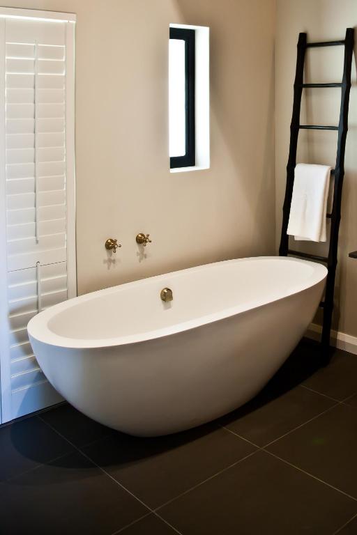 a large white bath tub in a bathroom at d'Olyfboom Guest House B & B in Paarl