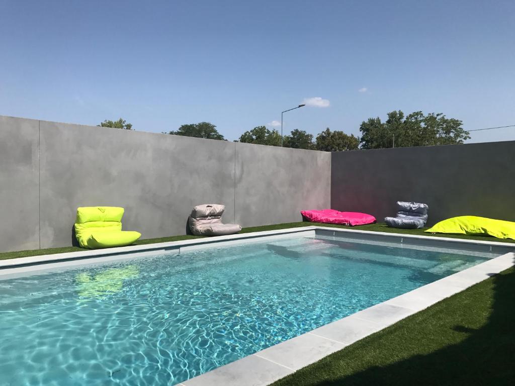 a swimming pool with chairs sitting next to a wall at Kyriad Direct Agen in Castelculier