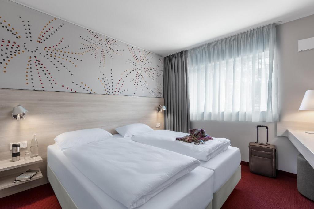 pokój hotelowy z dwoma białymi łóżkami w obiekcie Serways Hotel Steigerwald w mieście Wachenroth