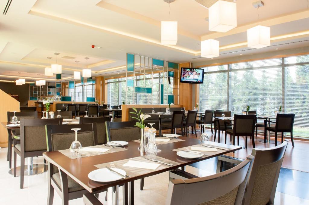 a restaurant with tables and chairs and a television at ISG Sabiha Gökçen Airport Hotel in Istanbul