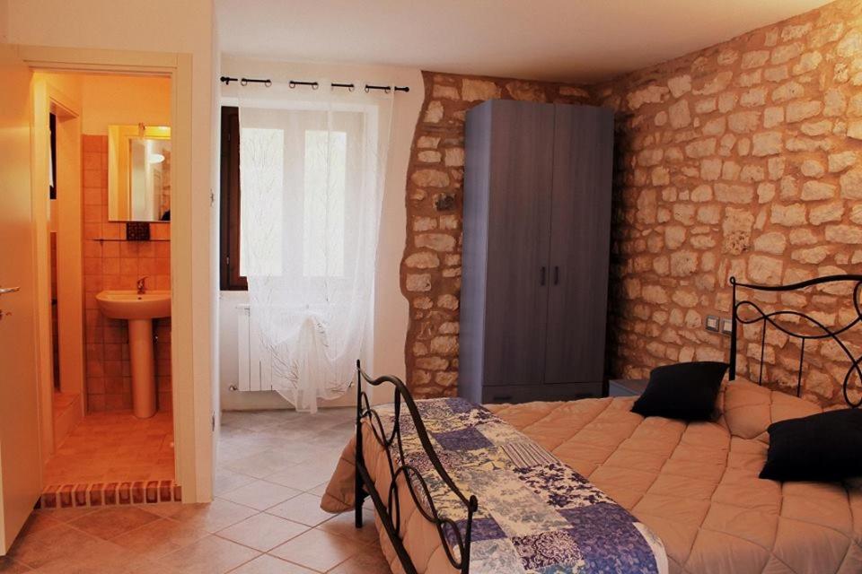 a bedroom with a bed and a stone wall at Casa Vacanze L'arco di Fondarca n.16 in Cagli