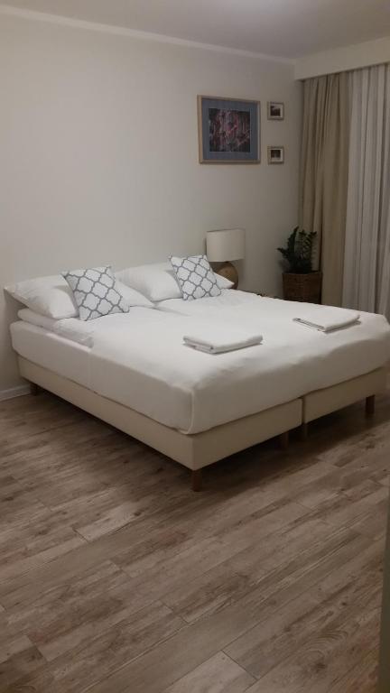 uma grande cama branca num quarto com piso em madeira em Apartament Grójecka em Varósvia