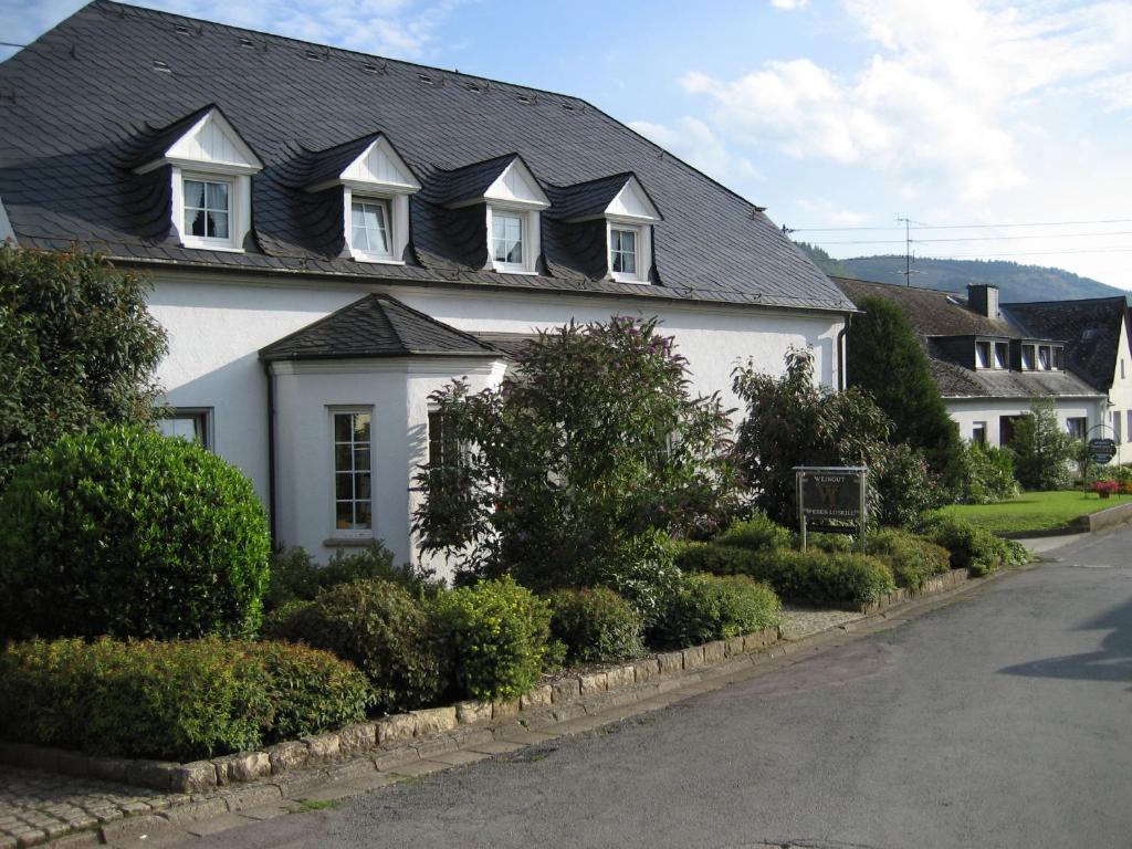 a white house with a black roof on a street at Gästehaus Weber-Loskill in Mehring