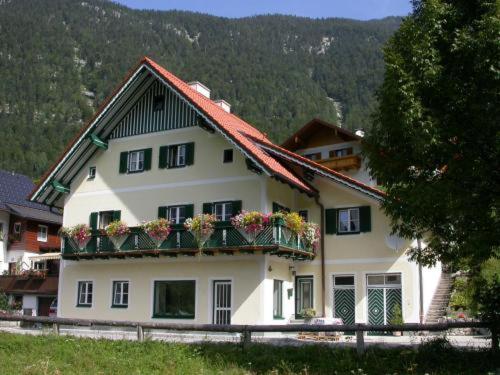 ein weißes Haus mit Blumenkästen auf dem Balkon in der Unterkunft Ferienhaus Feuerer in Obertraun