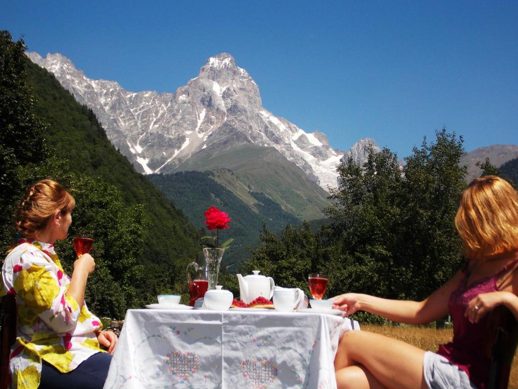 dos mujeres sentadas en una mesa frente a una montaña en Guest House Carpediem, en Becho