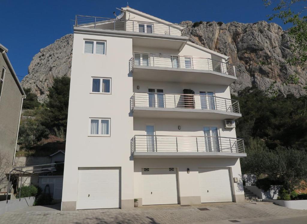 a white building with a balcony on a mountain at Apartments Kovacic in Omiš