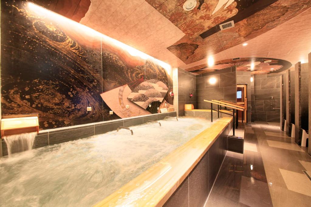 ein Badezimmer mit einer großen Badewanne und einem großen Wandgemälde in der Unterkunft Centurion Hotel&Spa Ueno Station in Tokio