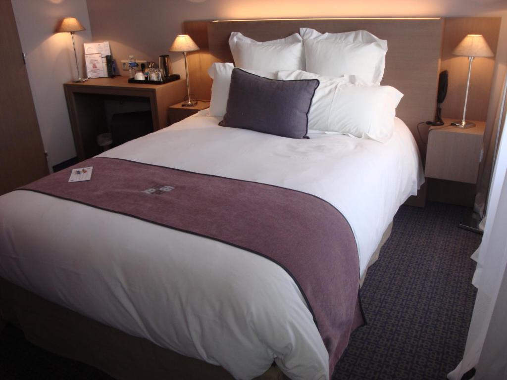 a hotel room with a large white bed with pillows at Best Western Hotel de la Breche in Niort