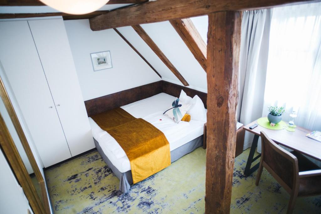Habitación pequeña con cama y escritorio. en Hotel Zirbelstube, en Núremberg