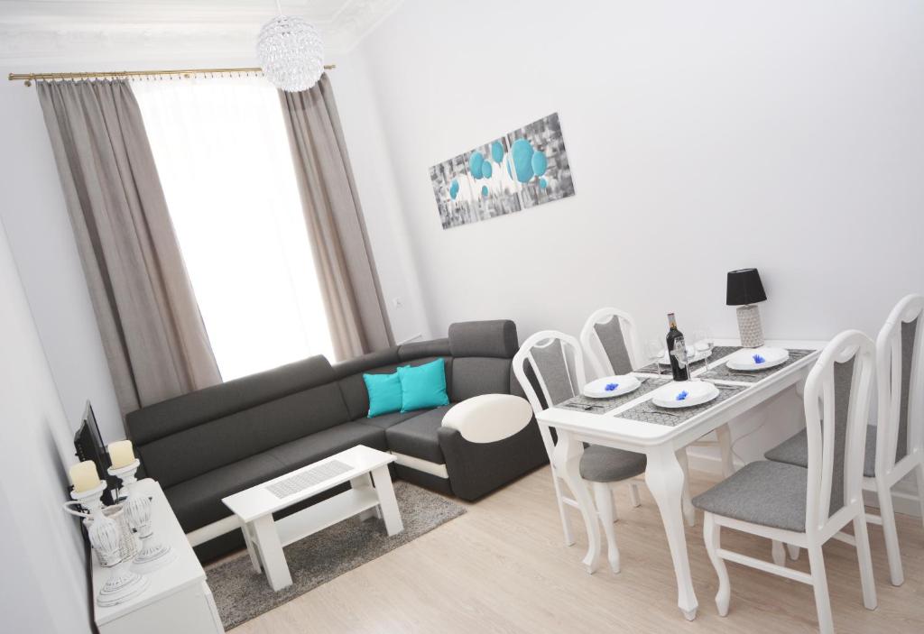 ein Wohnzimmer mit einem Sofa, einem Tisch und Stühlen in der Unterkunft Apartament Pod Kopernikiem II in Toruń