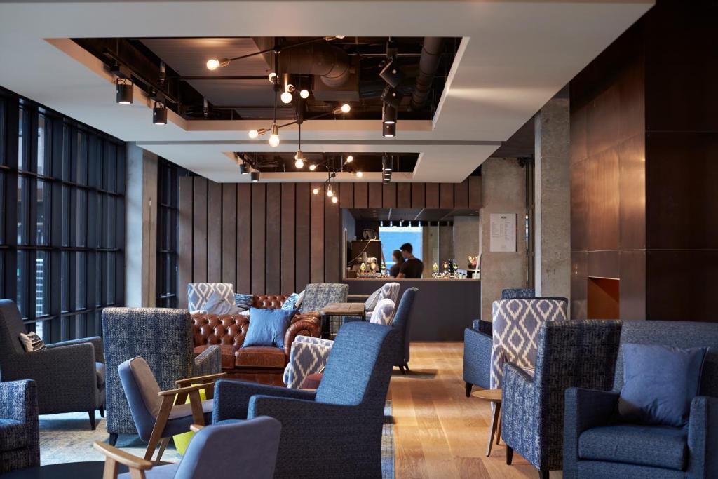 a waiting room with blue chairs and a bar at Steel House Copenhagen in Copenhagen