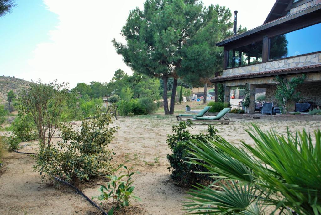 un patio con una casa con un banco y árboles en Saint Bernard, en Robledo de Chavela