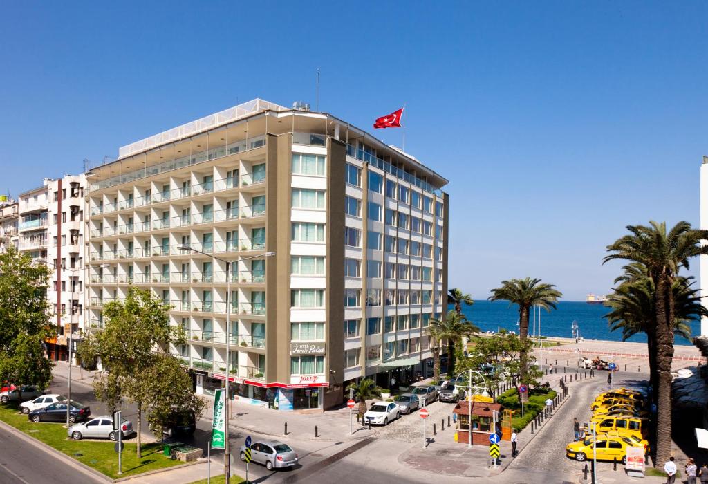 
a large building on a city street with palm trees at Izmir Palas Hotel in İzmir
