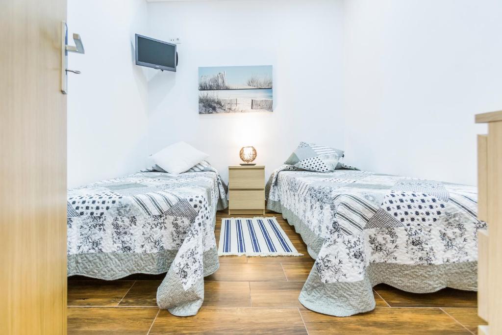 two beds in a room with white walls and wooden floors at Casa Laranjinha in Albufeira