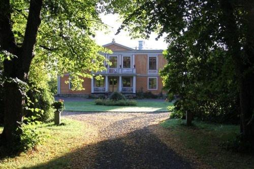 una gran casa de ladrillo con un patio con árboles en Mälby Säteri B&B, en Gnesta