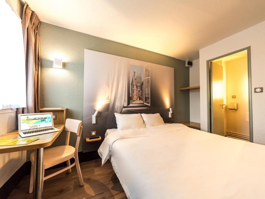 a hotel room with a bed and a desk with a laptop at B&B HOTEL Alencon Nord in Alençon