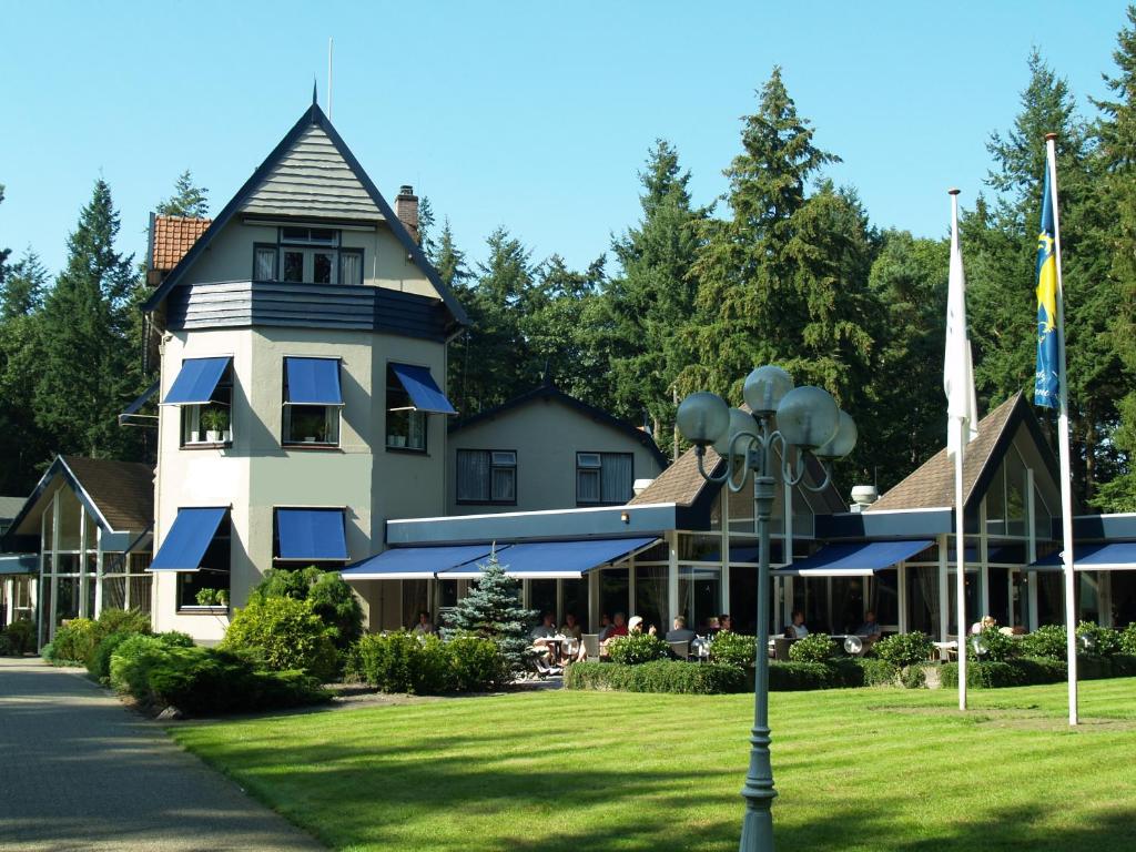 een groot wit huis met een gambrel bij Veluwe Hotel Stakenberg in Elspeet