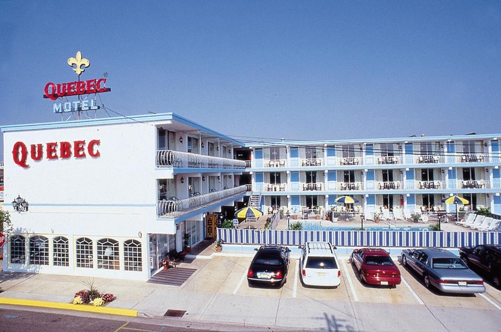 a large hotel with cars parked in a parking lot at Quebec Motel in Wildwood