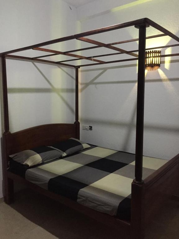 a wooden bed with a black and white canopy at Paddy House Villa Home Stay in Tangalle