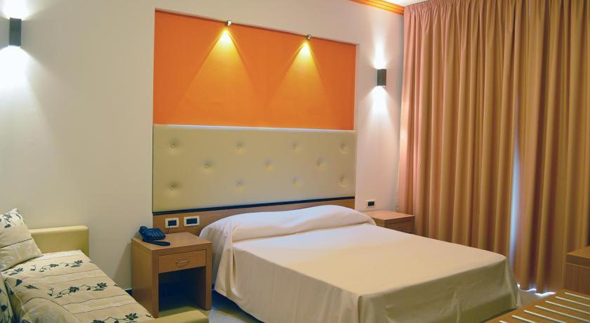 Habitación de hotel con 2 camas y pared de color naranja en Park Hotel Tyrrenian, en Amantea