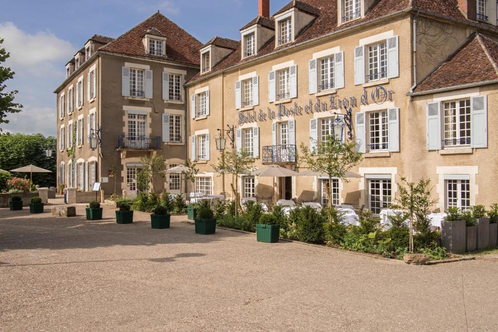 un grand bâtiment avec des plantes devant lui dans l'établissement Hôtel Restaurant De La Poste & Du Lion D'or, à Vézelay