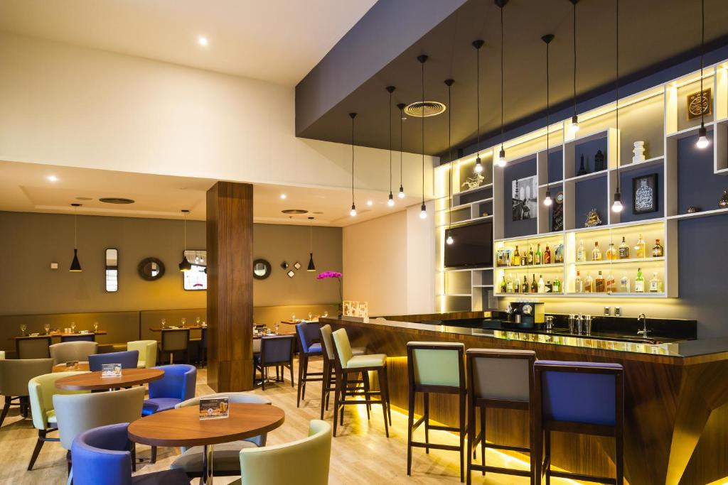 a restaurant with tables and chairs and a bar at Novotel Porto Alegre Tres Figueiras in Porto Alegre