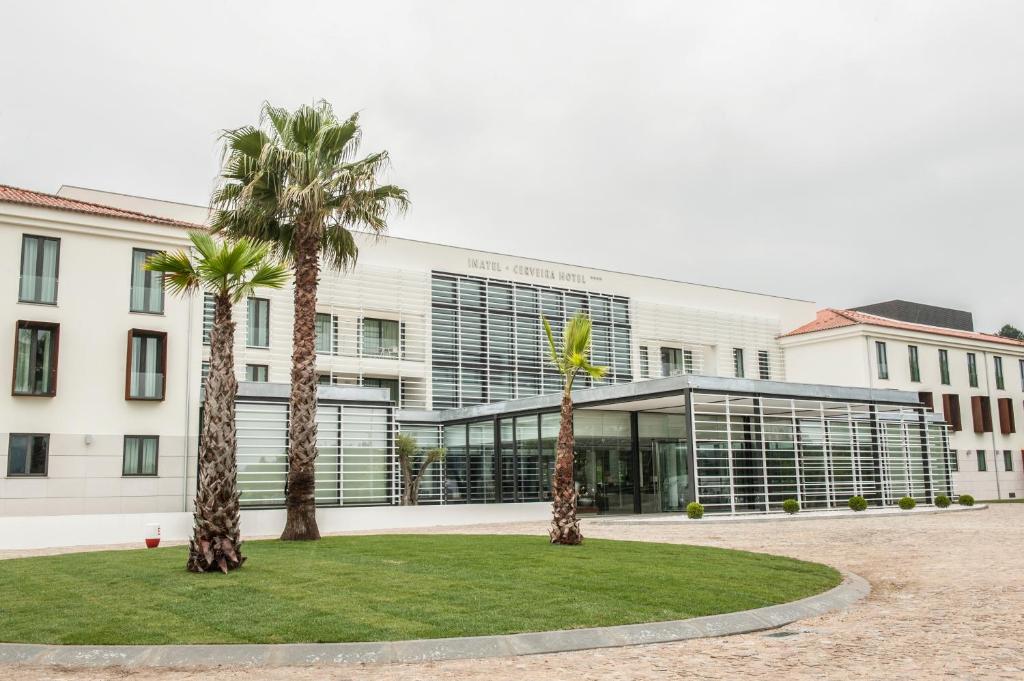 a building with palm trees in front of it at INATEL Cerveira Hotel in Vila Nova de Cerveira