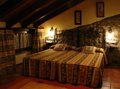 1 dormitorio con cama y pared de piedra en La Llobera Apartamentos, en Pendueles
