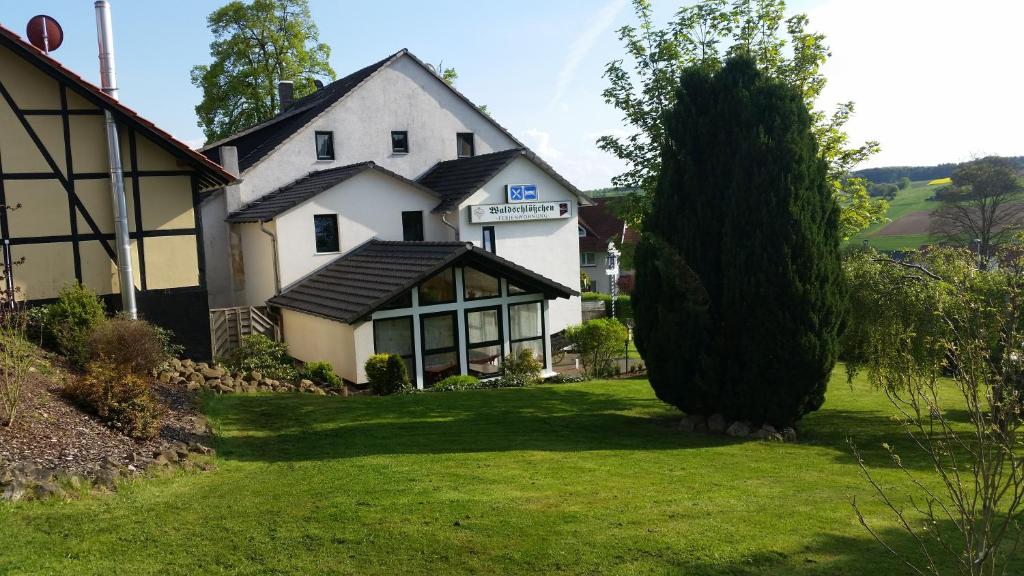 a large white house with a tree in the yard at Gasthaus Waldschlosschen in Wattenbach