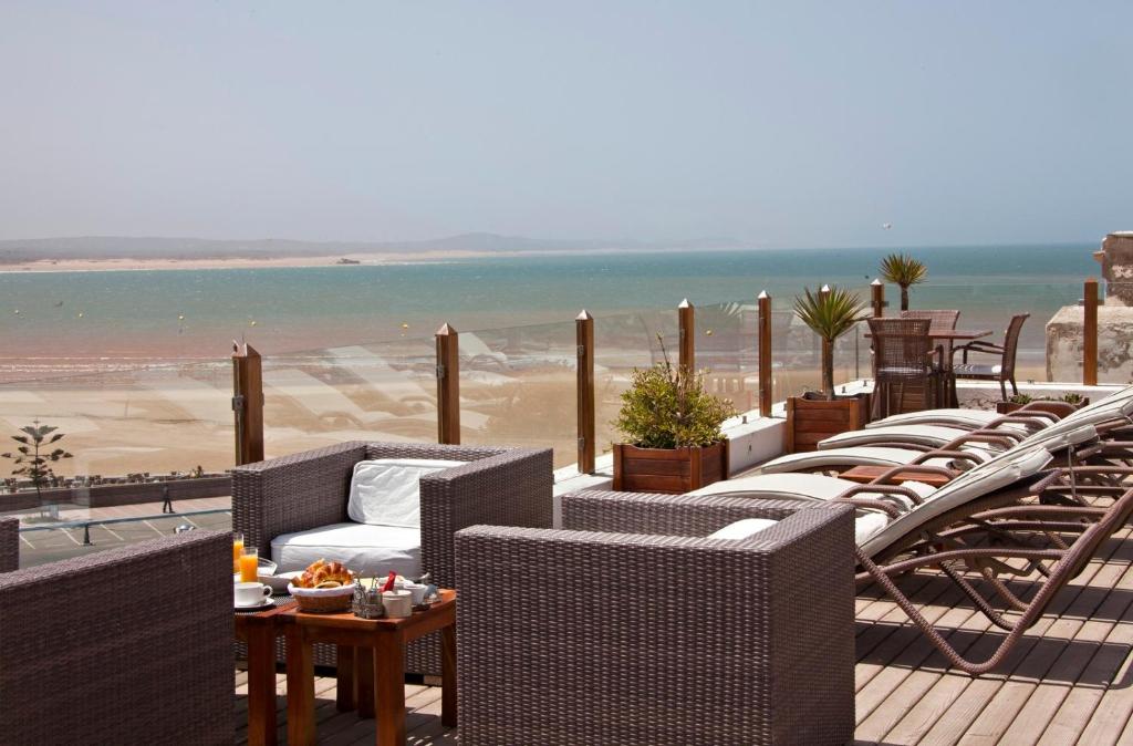- une rangée de chaises et de tables en osier sur une plage dans l'établissement Villa De L'Ô, à Essaouira