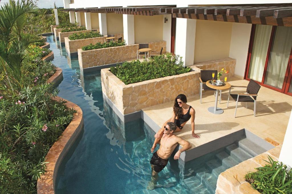 a man and a woman in the water in a swimming pool at Secrets Playa Mujeres Golf & Spa Resort - All Inclusive Adults Only in Cancún