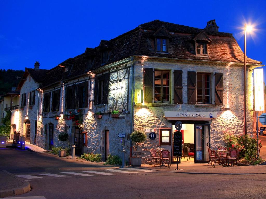 een oud stenen gebouw met verlichting op een straat bij Le Victor Hugo - Hôtel et Restaurant - Logis Hôtels in Saint-Céré