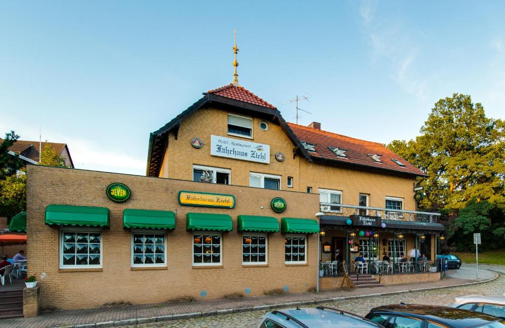 un grand bâtiment en briques avec des auvents verts dans l'établissement Hotel Fährhaus Ziehl, à Geesthacht