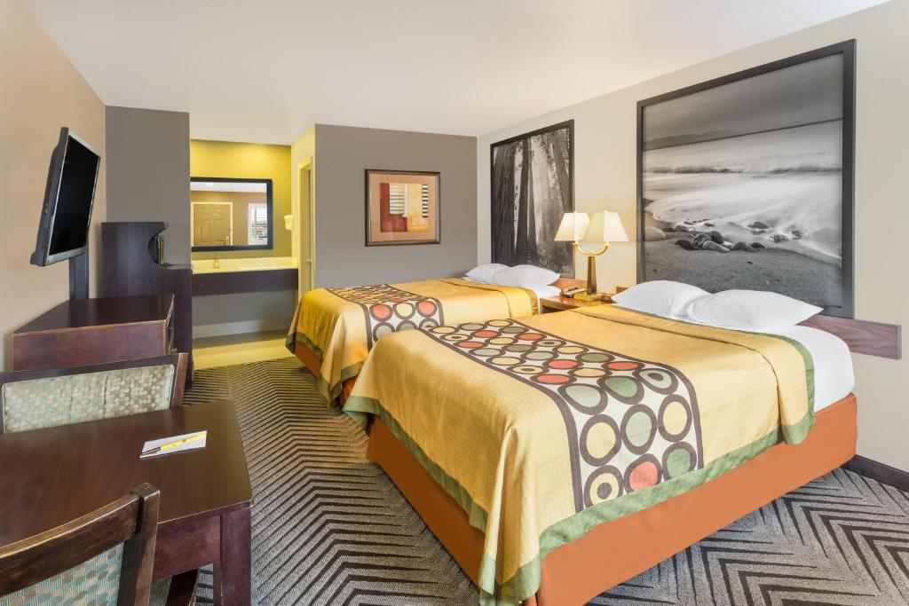 a hotel room with two beds and a desk at Super 8 by Wyndham Fortuna in Fortuna