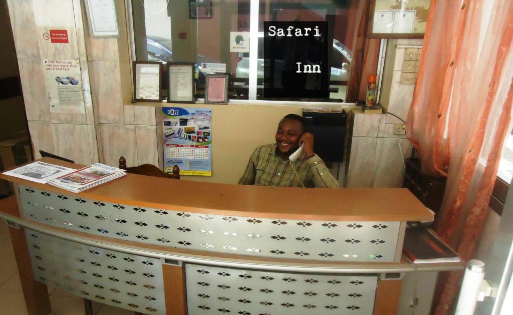 Un homme parlant sur un téléphone portable derrière un comptoir dans l'établissement Safari Inn, à Dar es Salaam