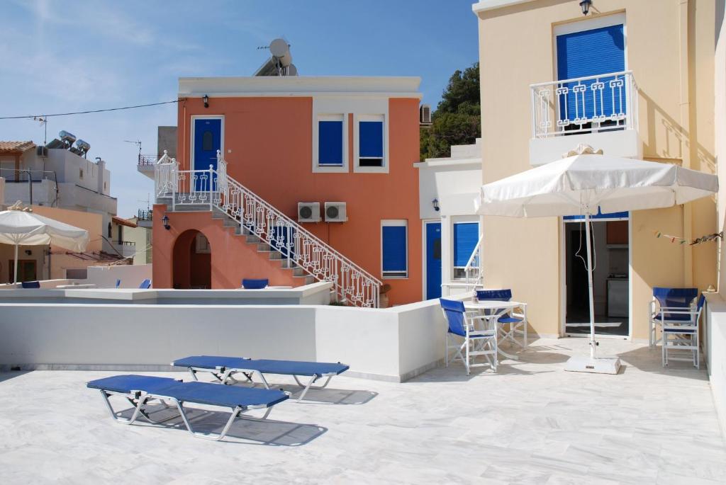 a patio with chairs and an umbrella and a building at Limani Apartments in Plakias