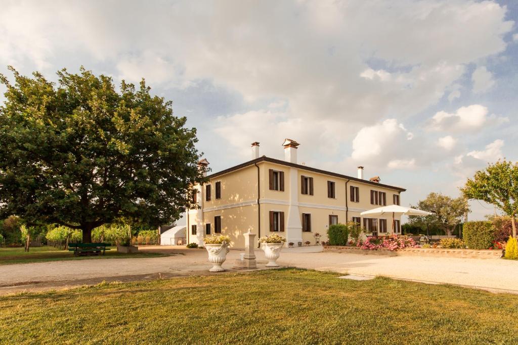 una gran casa blanca con un árbol delante en AgriB&B Corte Burchio, en Adria