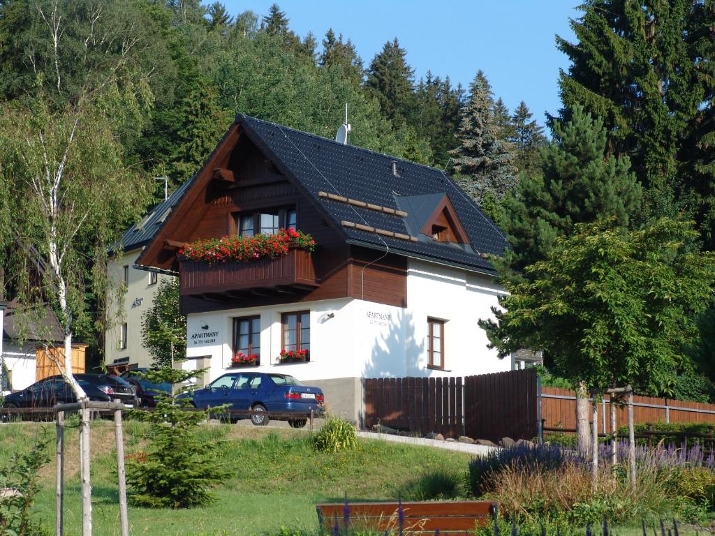 une maison blanche avec un toit noir dans l'établissement Apartmány U Kamínku, à Janské Lázně