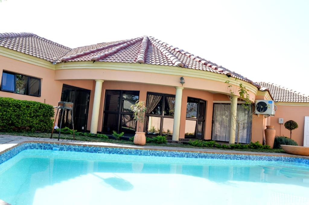 a house with a swimming pool in front of a house at Golden Door Villa in Gaborone