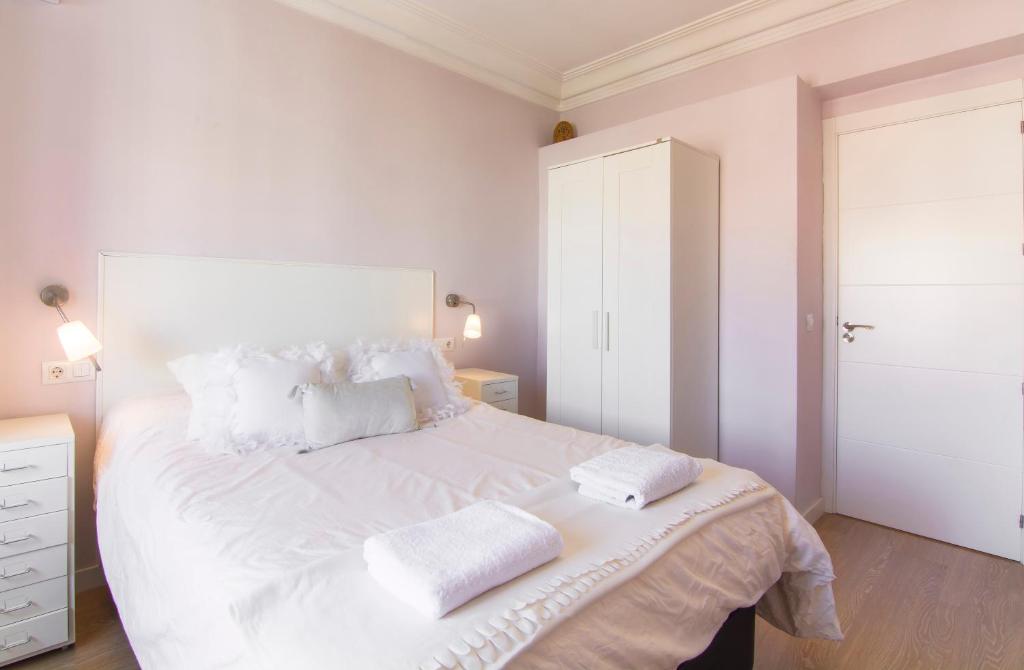 una camera bianca con un grande letto bianco con due cuscini di Atico Atocha con Terraza a Madrid
