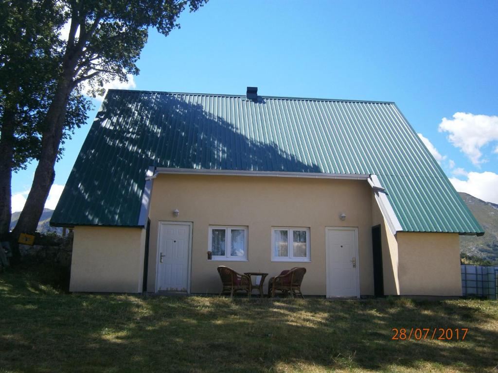 uma casa com duas cadeiras e um telhado verde em Wolf Apartment em Žabljak