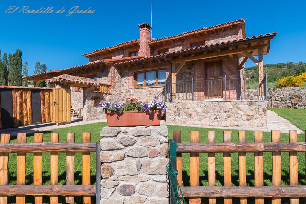 a house with a fence and two wooden benches at El Rondillo de Gredos in Hoyos del Collado