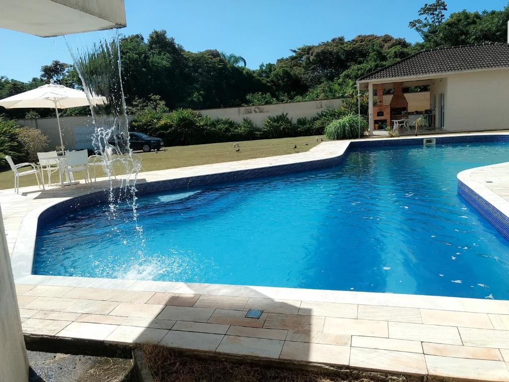 a swimming pool with a fountain in a yard at BertAkua in Bertioga